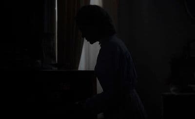 a person standing in a dark room with a piano