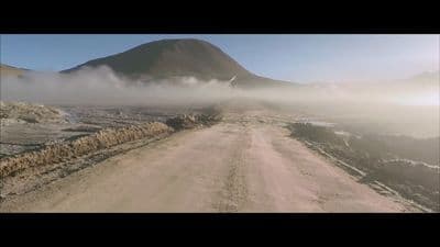 a dirt road with a mountain in the background