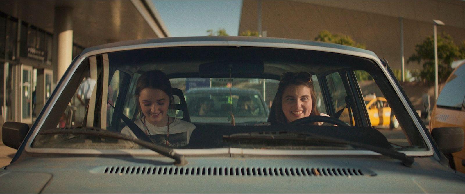 two women sitting in a car talking to each other