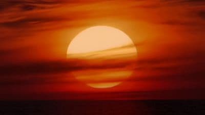 the sun is setting over the ocean on a cloudy day