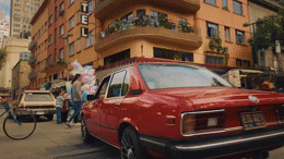a red car parked in front of a tall building
