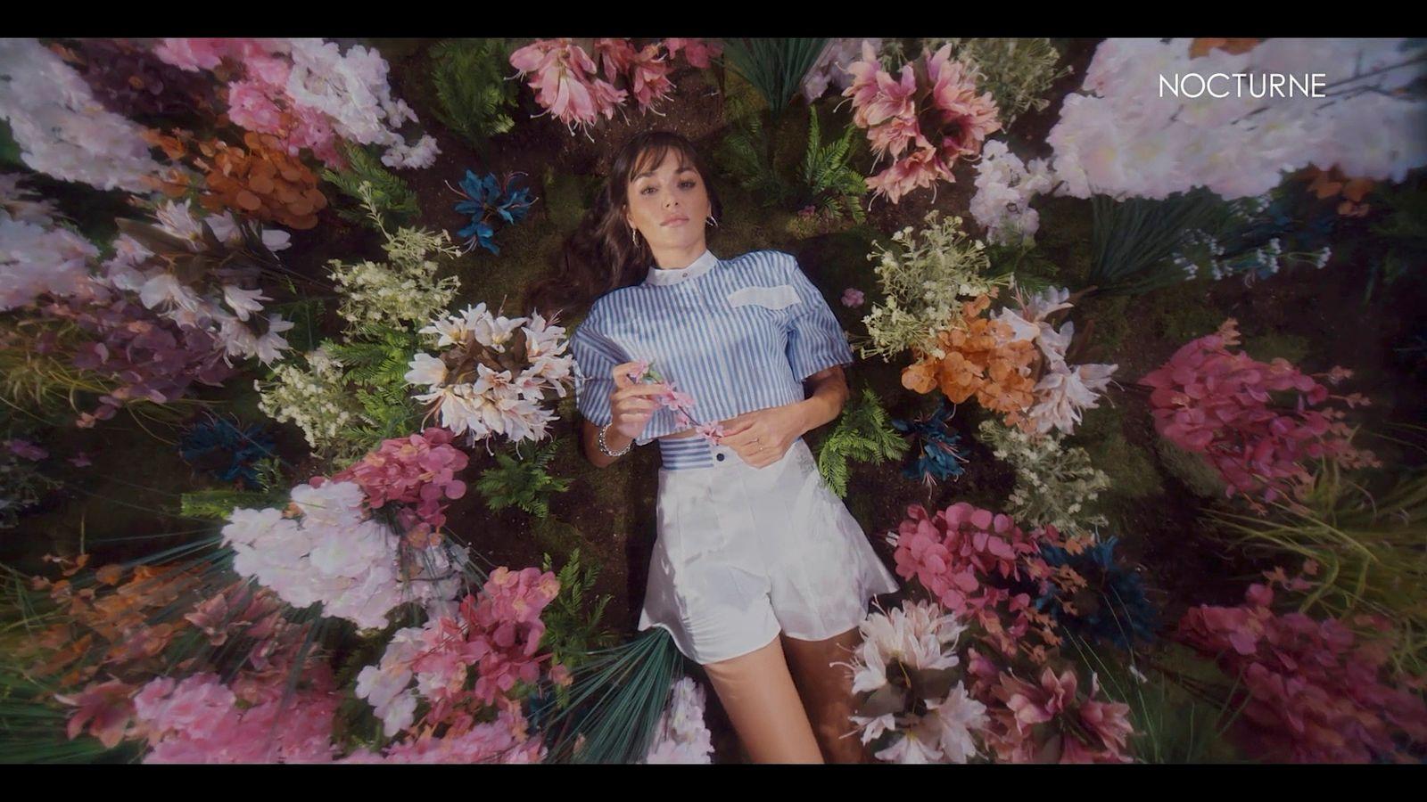 a woman standing in front of a bunch of flowers