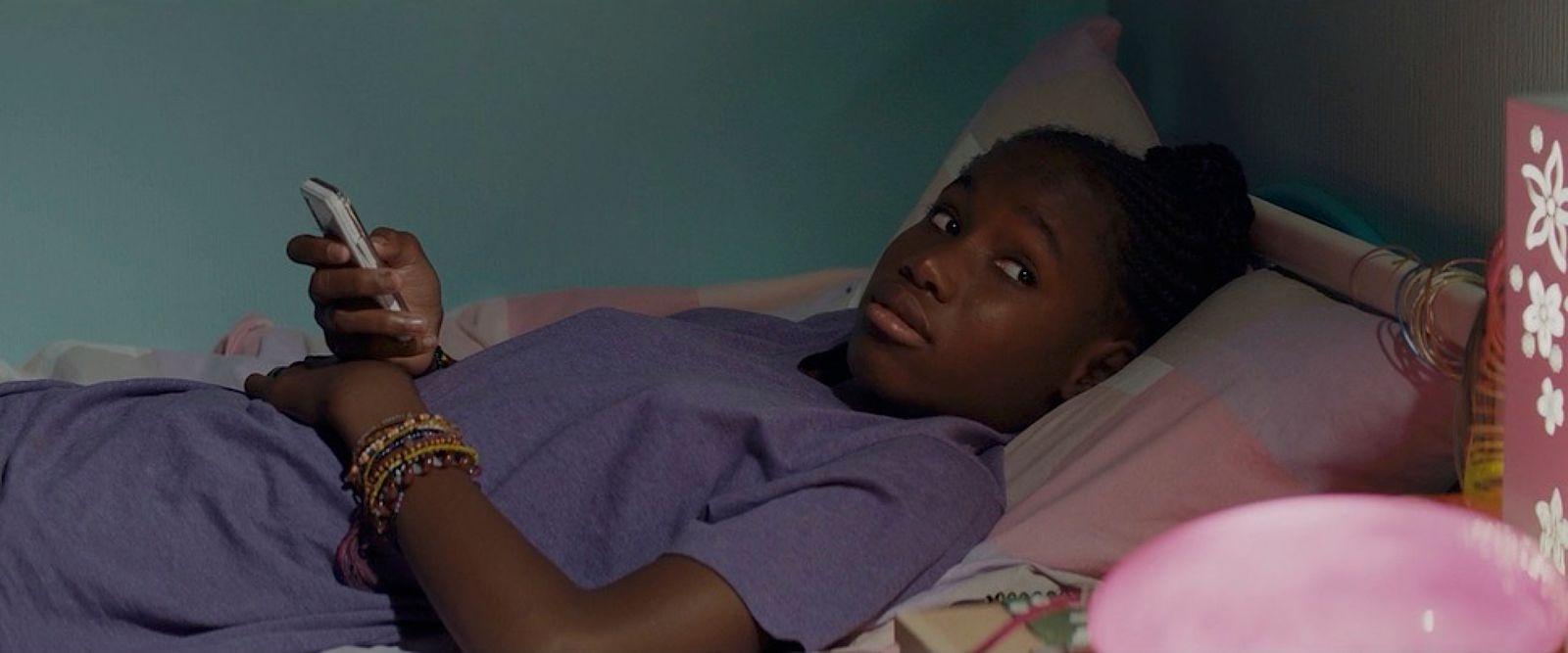 a woman laying in bed holding a cell phone