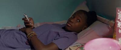 a woman laying in bed holding a cell phone