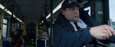 a man sitting on a bus with a hat on