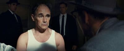 a man in a tank top looking at another man in a suit