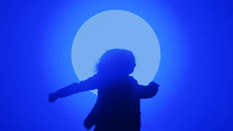 a silhouette of a person holding a large object in front of a blue background