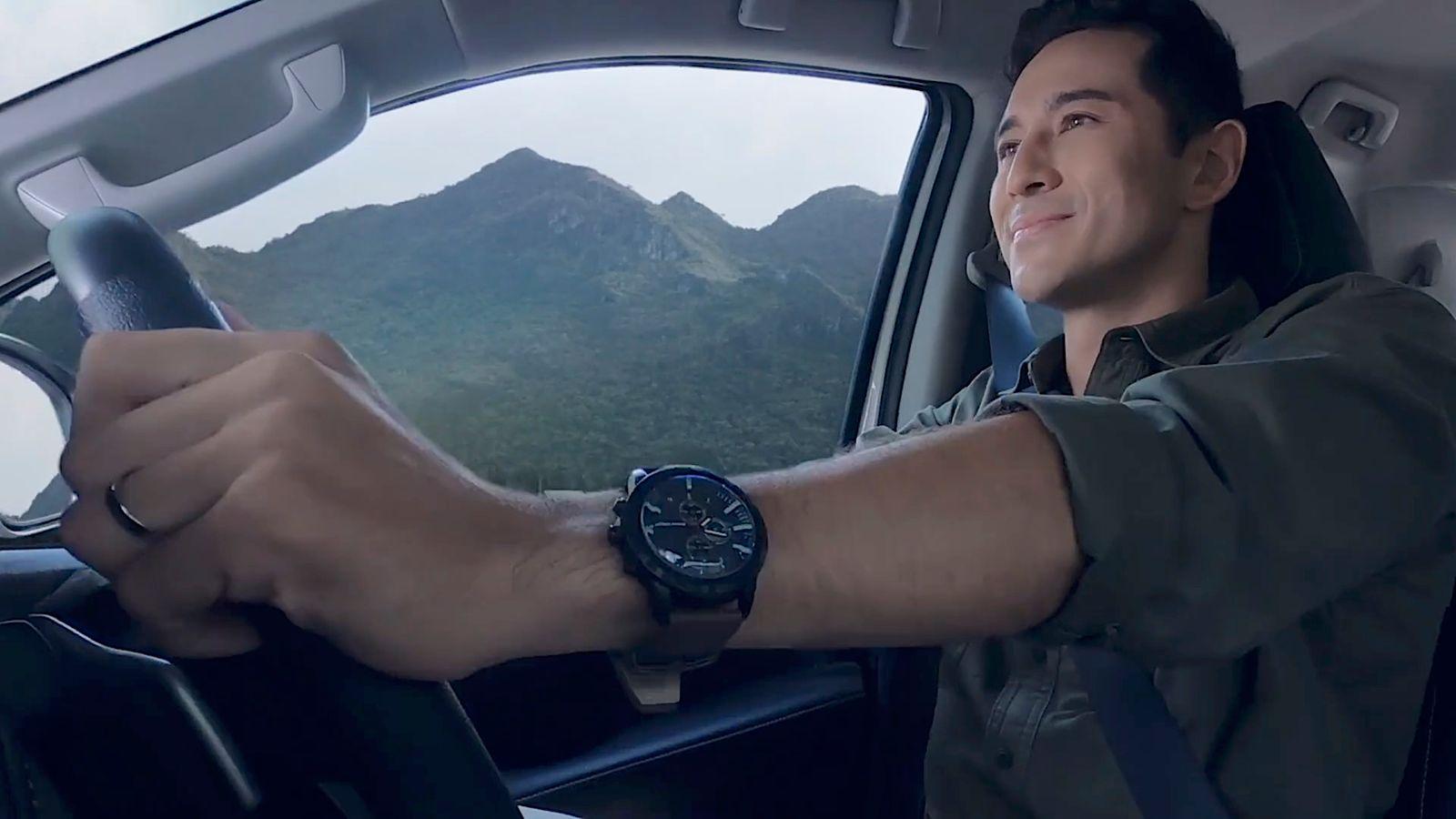 a man driving a car with mountains in the background