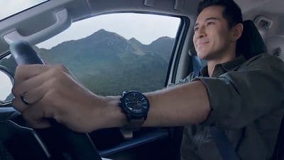 a man driving a car with mountains in the background