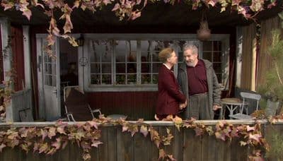 a man and a woman standing in front of a house