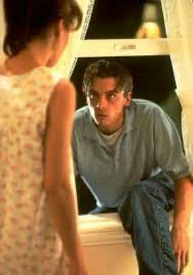 a man sitting on a window sill looking at a woman