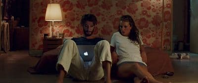 a man and a woman sitting on the floor with a laptop