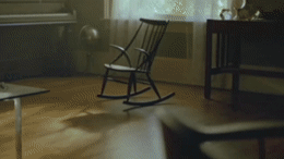 a rocking chair sitting in a living room next to a piano