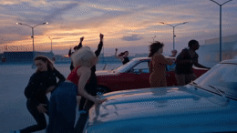 a group of people standing around a parked car