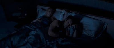 a man and a woman laying in bed in the dark
