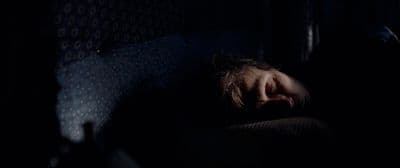 a person sleeping in a dark room with their head on a pillow