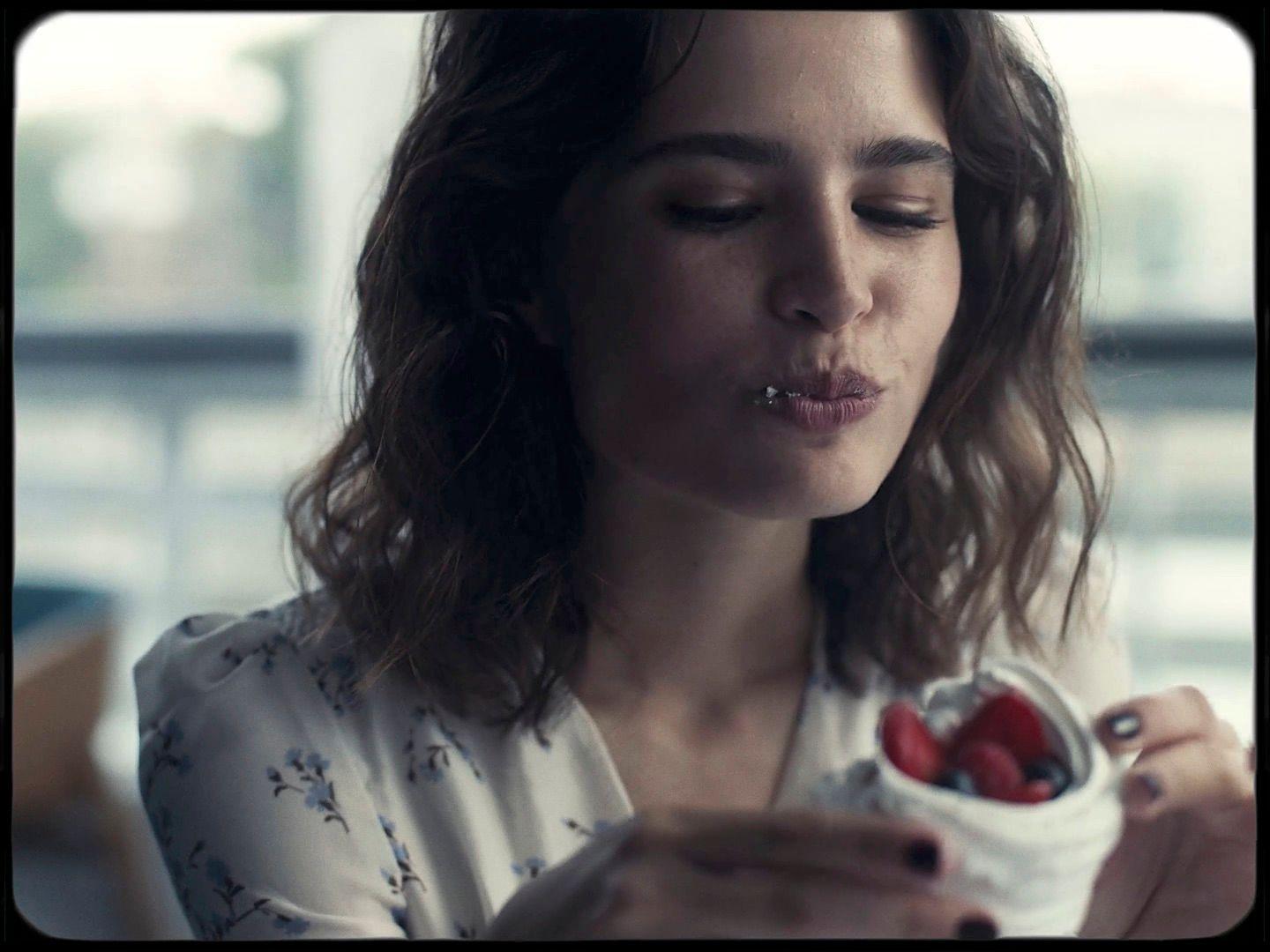 a woman holding a container of strawberries in her hand
