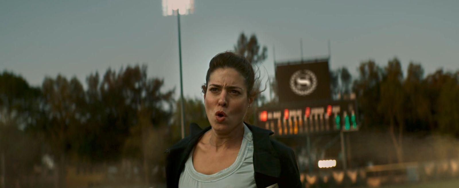 a woman making a surprised face in front of a stadium