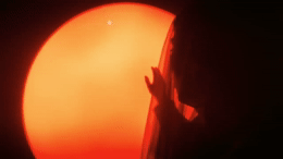 a close up of a person's hand with the sun in the background