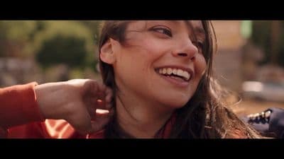 a close up of a person smiling and touching her ear