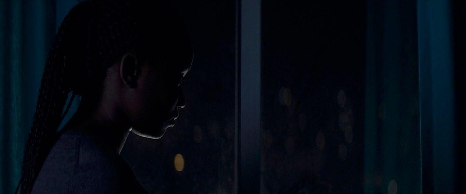 a woman standing in front of a window in the dark