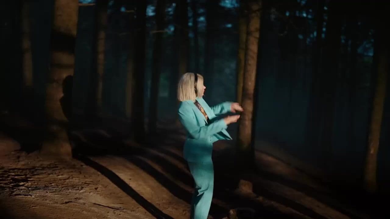 a woman in a blue suit is dancing in the woods