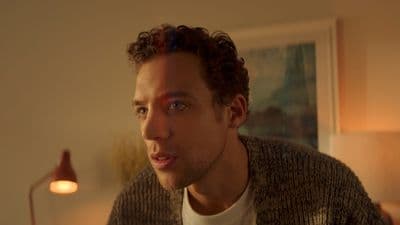 a man with curly hair wearing a sweater
