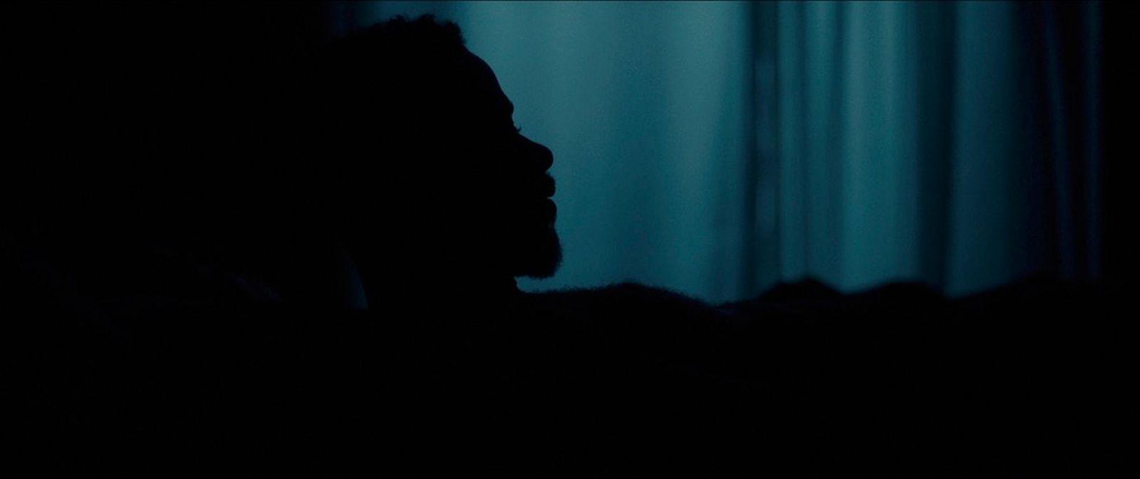 a silhouette of a person in front of a curtain