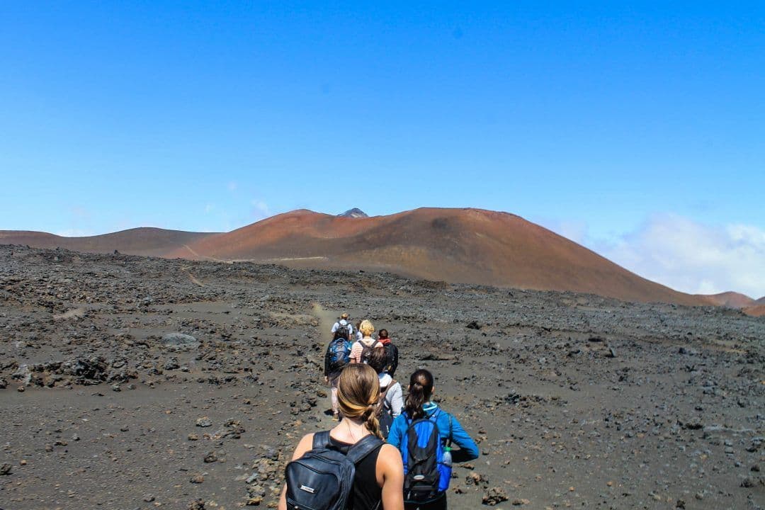 a group of people walking across a dirt field