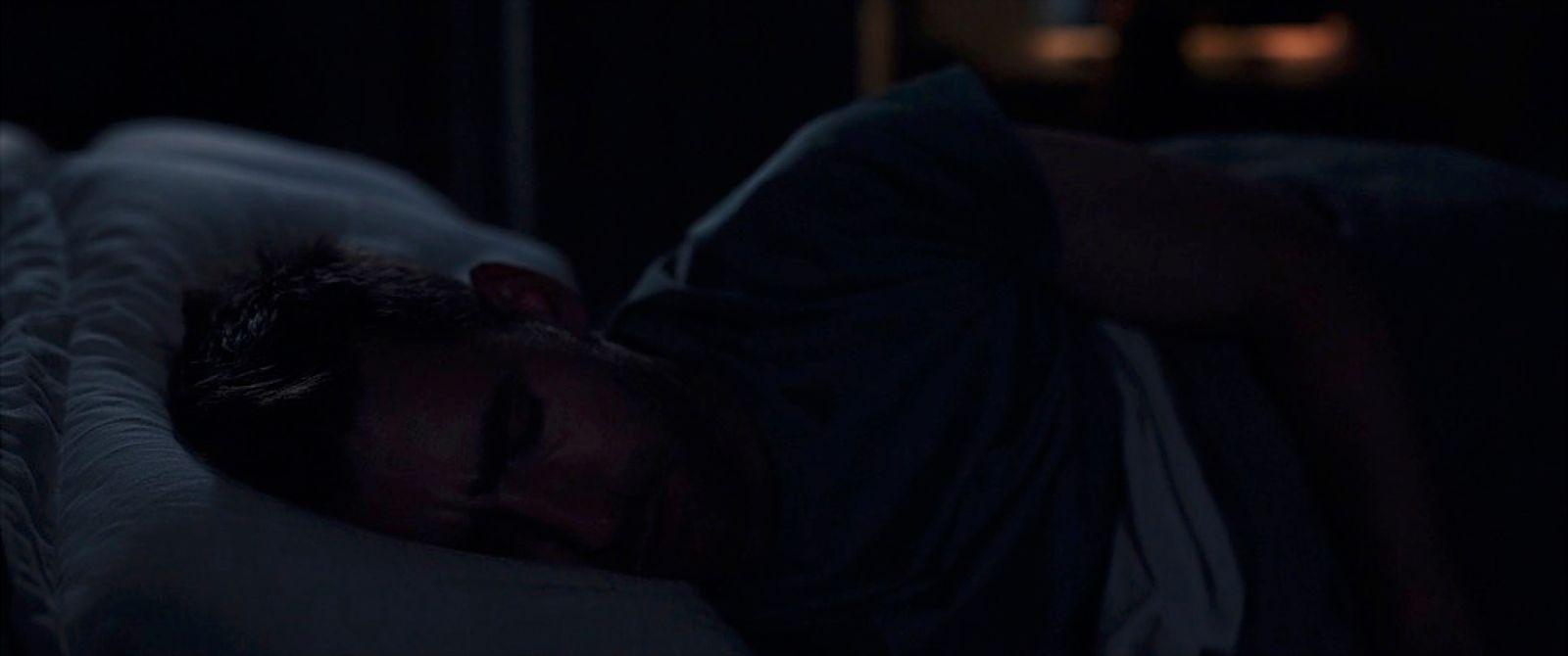 a man laying in bed with his eyes closed