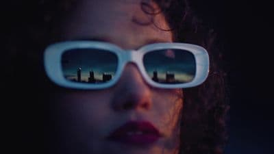 a woman wearing sunglasses with the reflection of a city in them