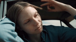 a woman sitting in a car with her hand on her head