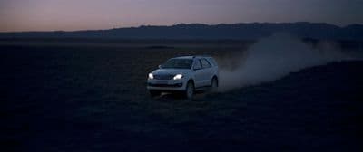 a white suv driving through the desert at night