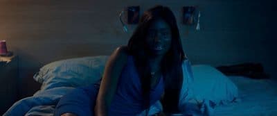 a woman sitting on a bed in a dark room
