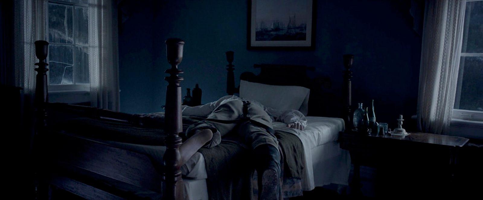 a person laying on a bed in a dark room