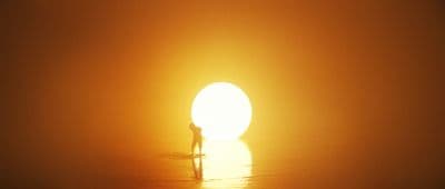 a person standing in the water at sunset