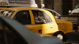 a taxi cab driving down a busy city street