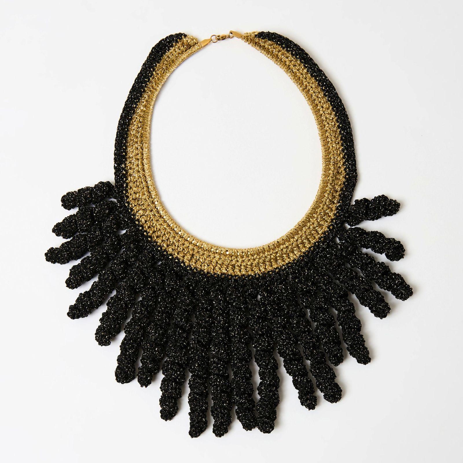a black and gold necklace on a white surface