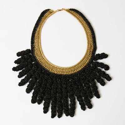 a black and gold necklace on a white surface