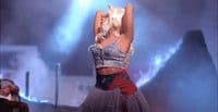 a woman in a skirt on stage with her arms in the air
