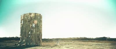 a wooden structure in the middle of a field