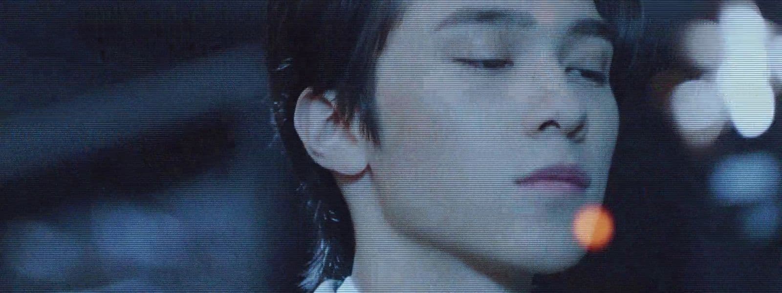 a man with his eyes closed in a dark room