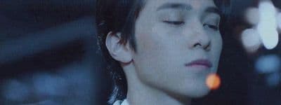 a man with his eyes closed in a dark room