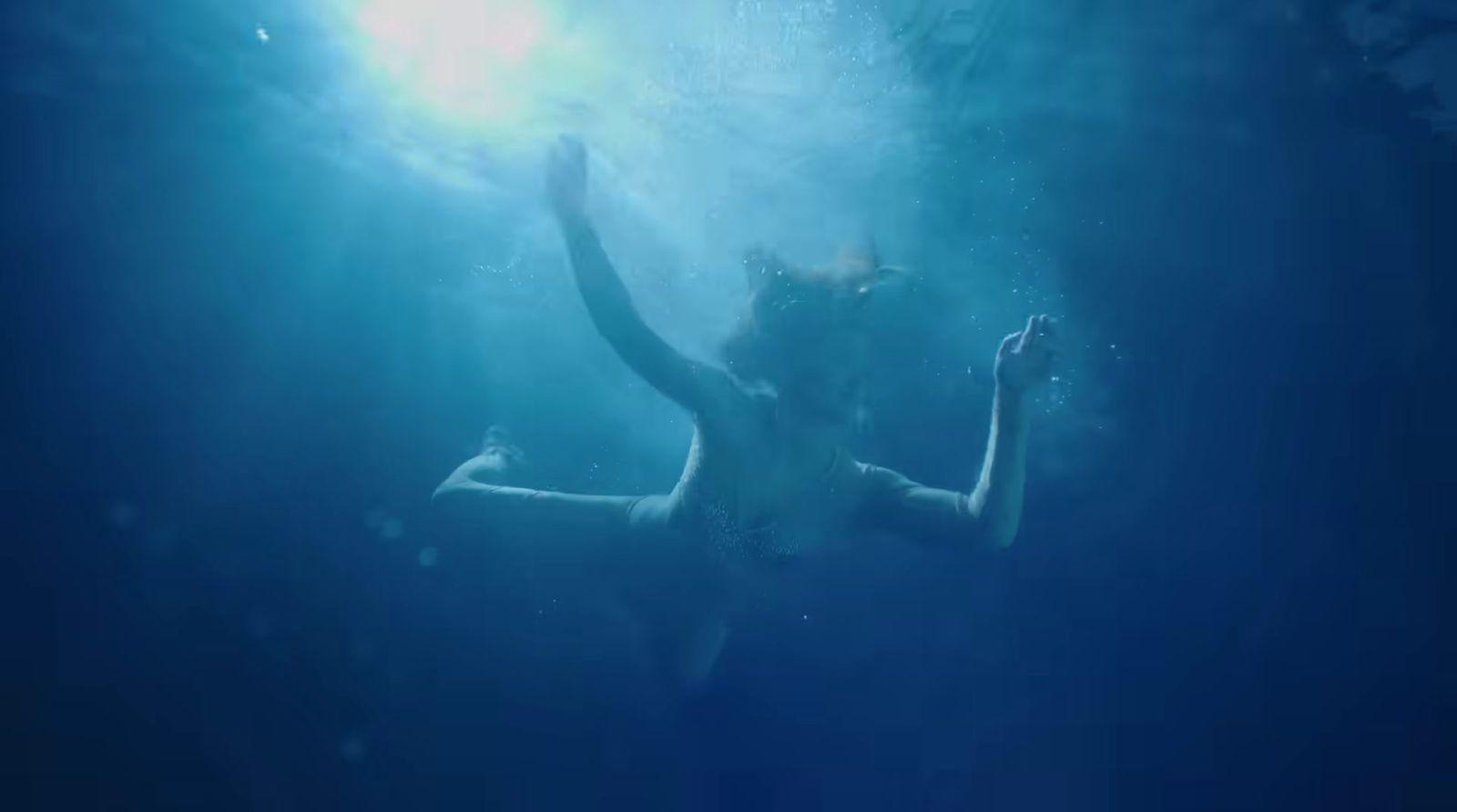 a woman in a body of water with her arms in the air