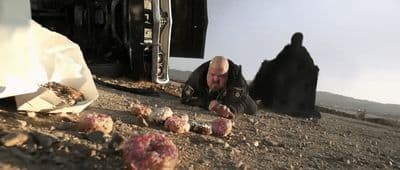 a man sitting on the ground in front of a truck