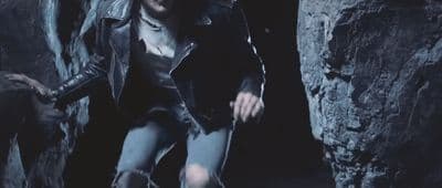 a man in a leather jacket is walking through a cave