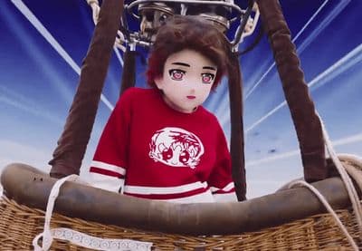 a doll in a red shirt sitting in a hot air balloon