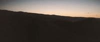 a black and white photo of a mountain at sunset