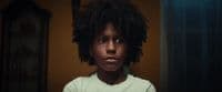a young boy with curly hair standing in front of a mirror