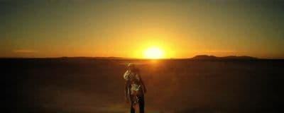 a person standing in the middle of a desert at sunset